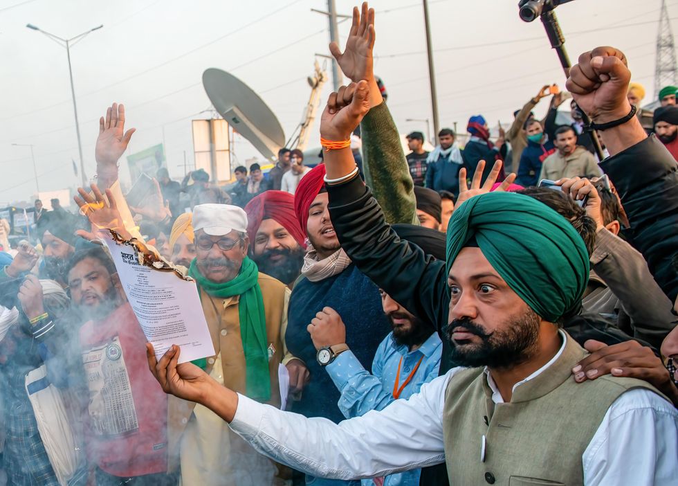 Protesters burning a copy of the farm laws