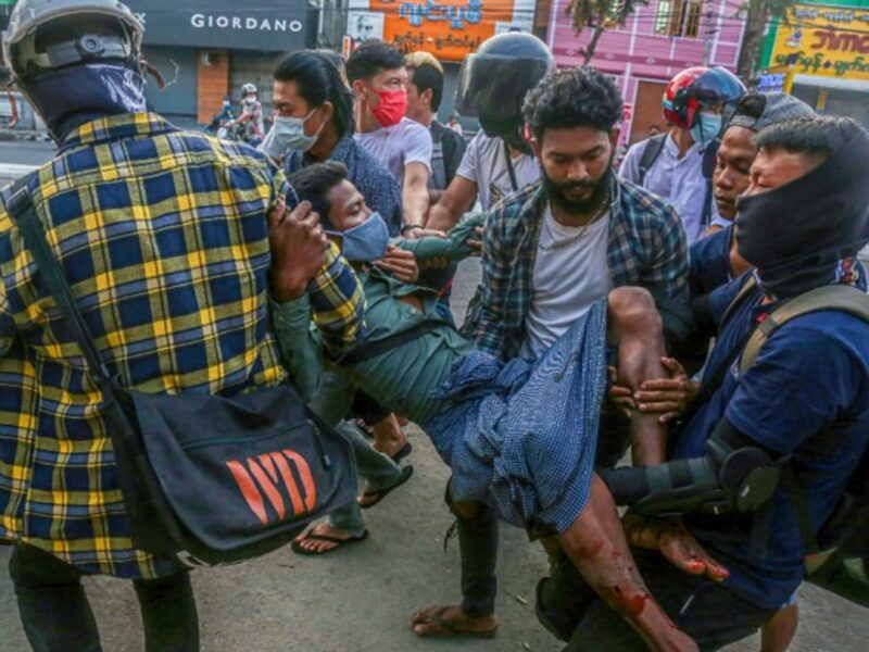 Protesters carry a wounded man after police and military opened fire on the crowd, killing 18, during the military coup demonstrations in Yangon, Myanmar.