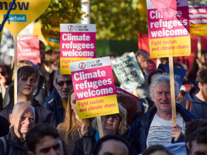 Protesters hold 'Climate refugees welcome' placards outside Shell HQ, London, UK. ​