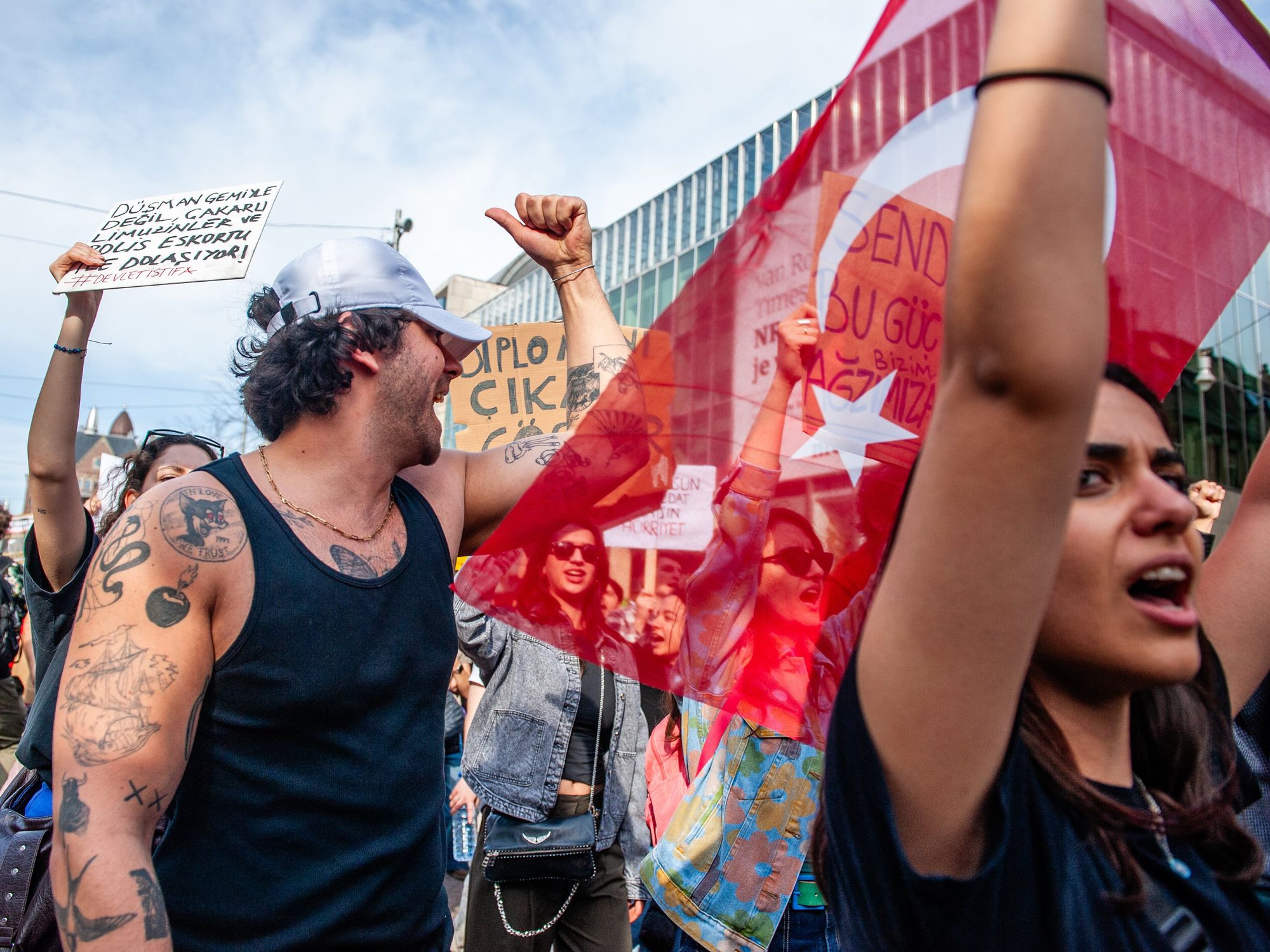 protesters holding signs and turkish flags are seen at eye level