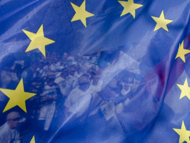 Protesters seen through a flag of Europe during a demonstration in Budapest