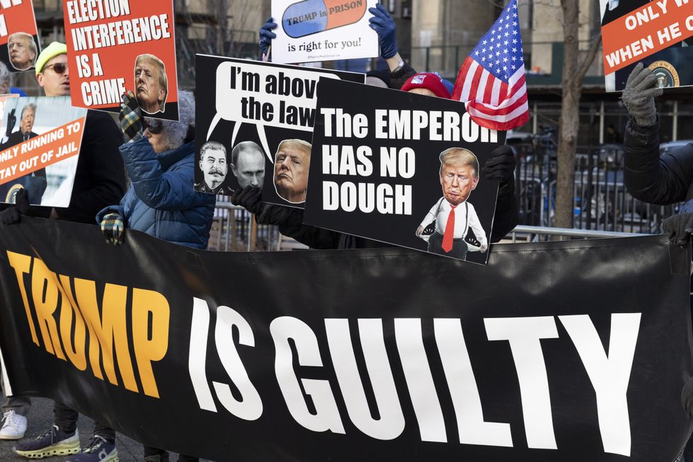 Protesters with the activist group Rise & Resist hold signs and banners outside the Manhattan Criminal Courthouse.