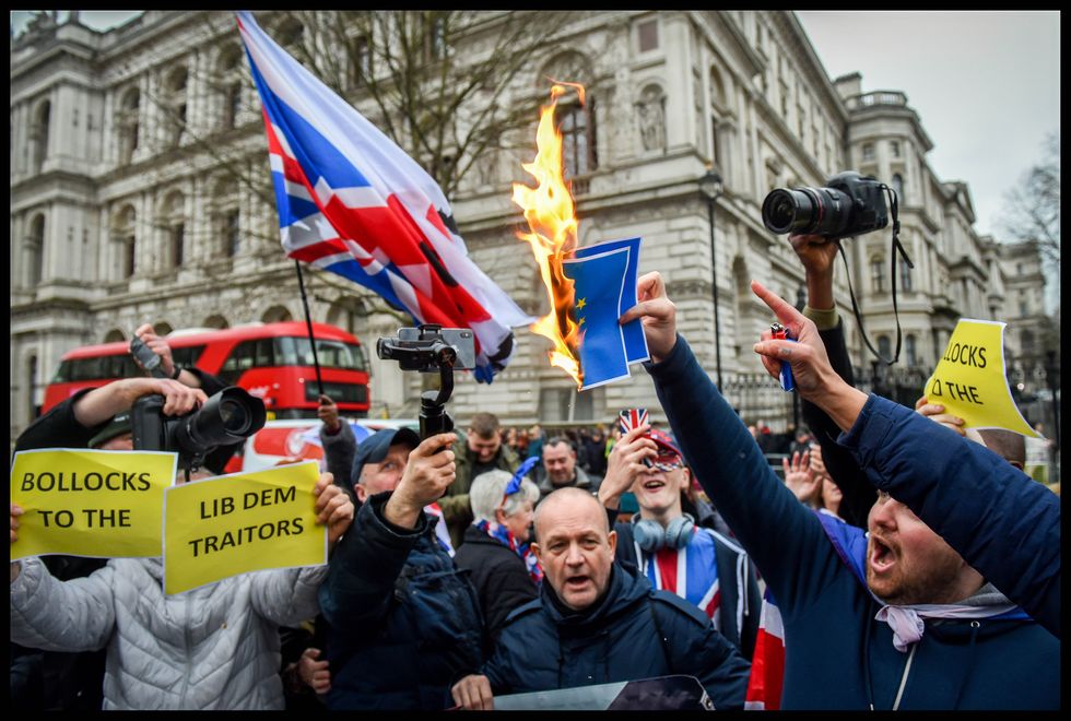 Protestors, burning picture of EU flag, flying the british flag, and demonstrating for brexit