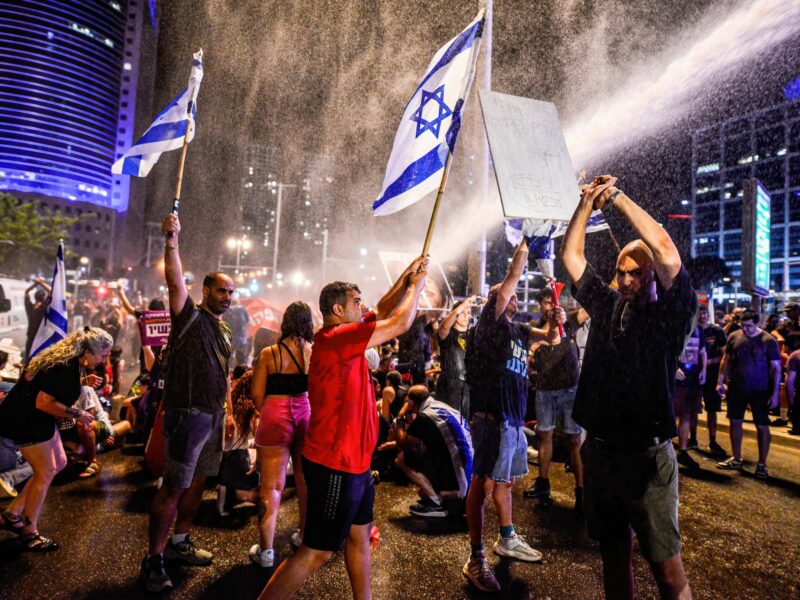 Protestors wave the Israeli flag as police use water cannons to disperse the demonstration from Kaplan junction.
