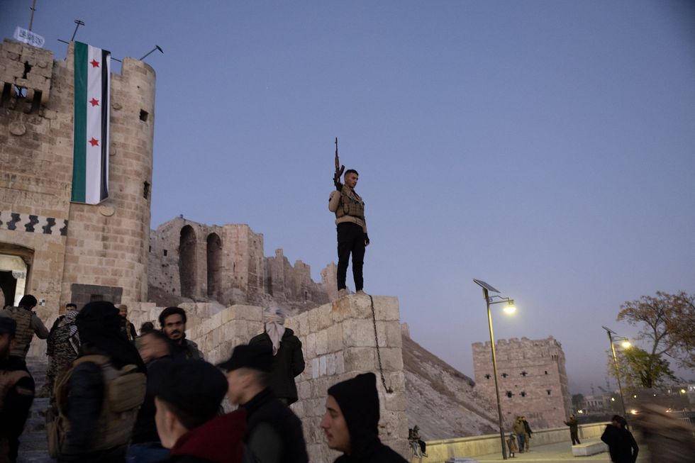 Rebel fighters stand guard outside Aleppo's old citadel, Syria after its seizing by Islamist HTS fighters and their Turkish-backed allies.