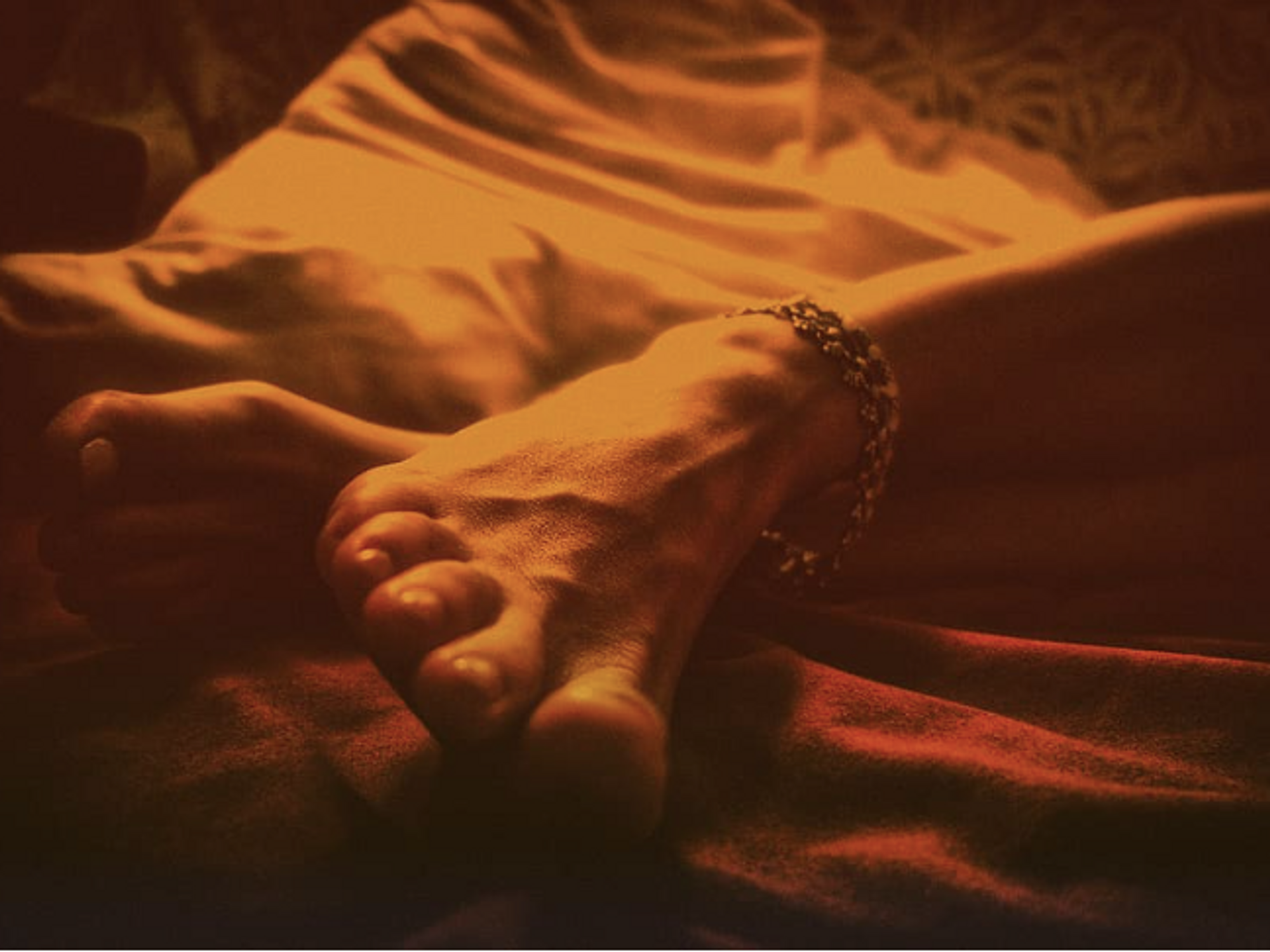 red tinted photo of feet on a bed