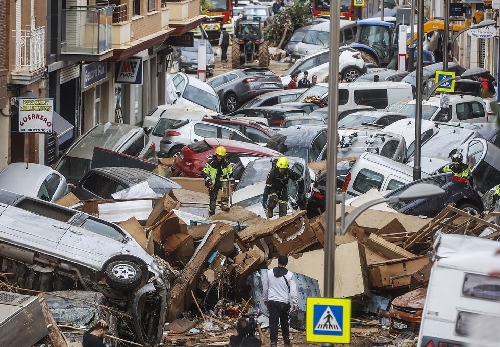 Rescue workers climb over dozens of cars piled up like toys after the floods in Sedavi near Valencia.