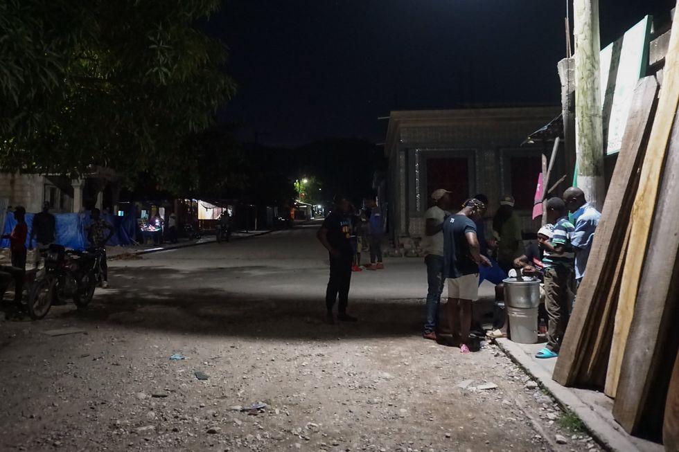 Residents play dominoes under the streetlights along Maniche’s main street.