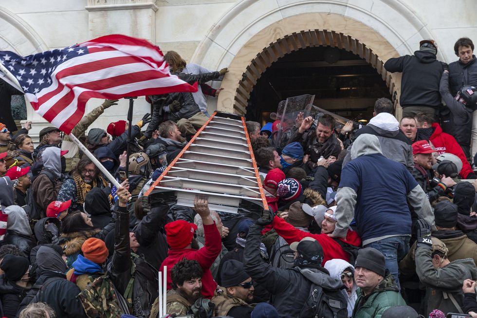 Rioters try to use a big ladder trying to enter Capitol building through the front doors on January 6, 2021.
