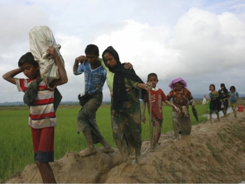 Rohingya refugees walk through the mud