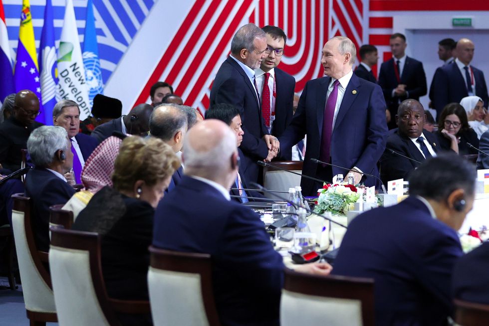 Russian President Vladimir Putin and Iranian President Masoud Pezeshkian shake hands during the BRICS Summit in Kazan, Russia.