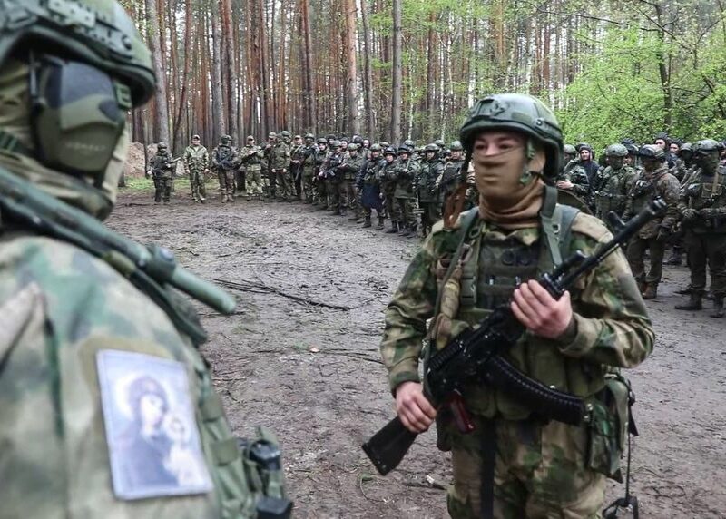 Russian servicemen line up with assault rifles.