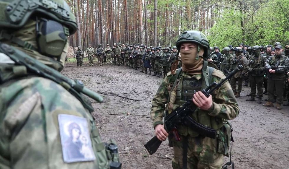 Russian servicemen line up with assault rifles.