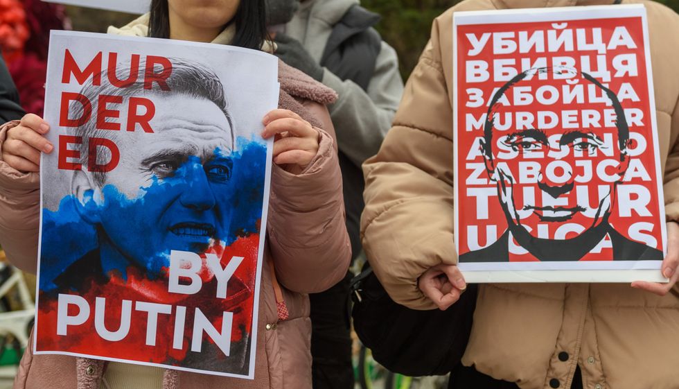 Russians hold placards protesting against Alexei Navalny death and anti-war protests.