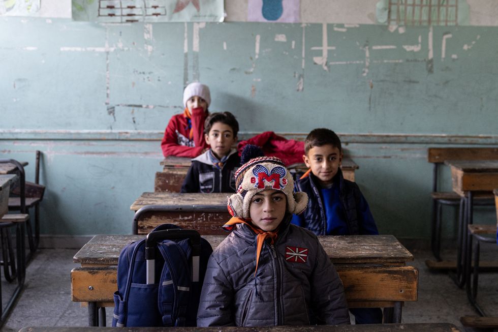 Schoolchildren sit in a dilapidated classroom