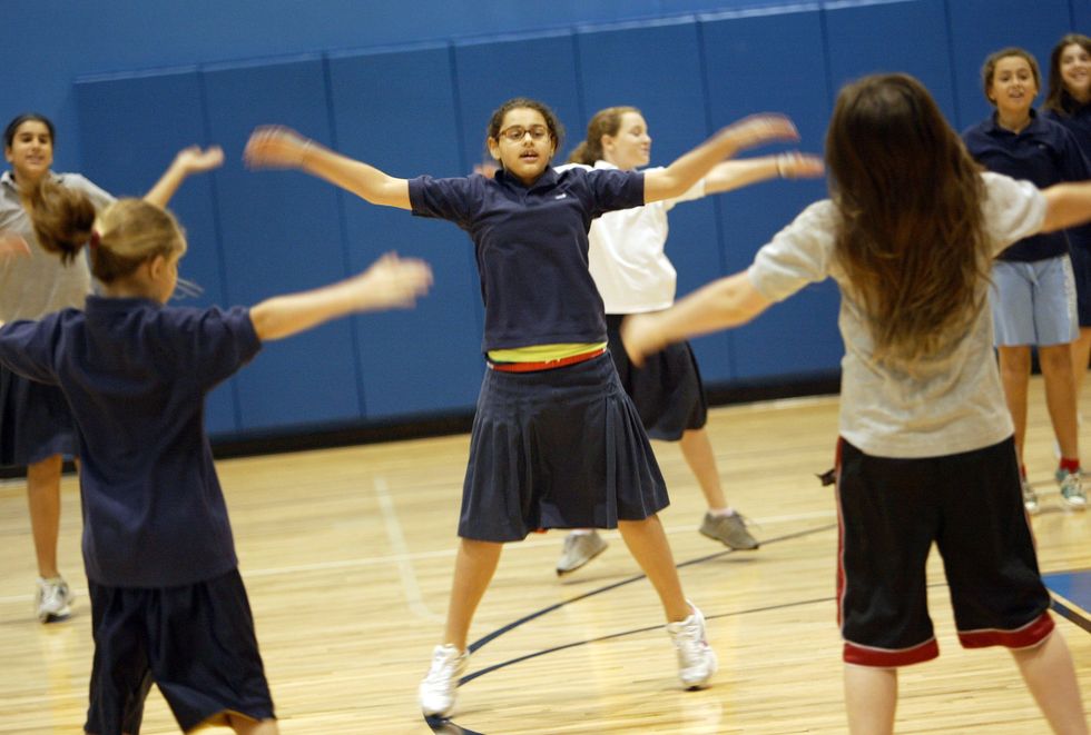 Sixth grade girls do jumping jacks warm in the gym before a PE class at Hillel Day School in Boca Raton.