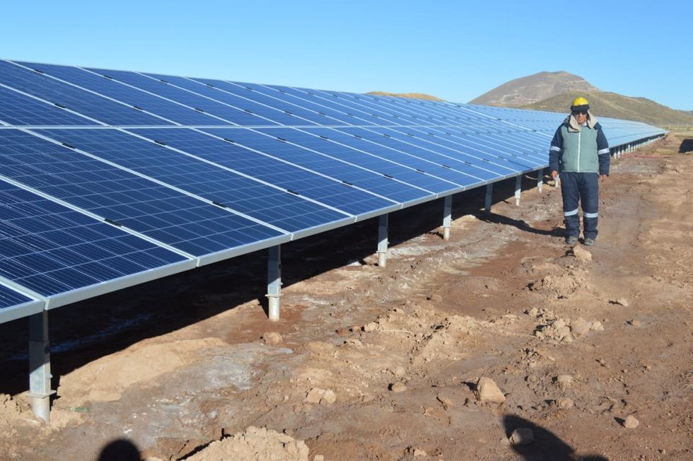 Solar plant worker in Bolivia stands next to solar panels.