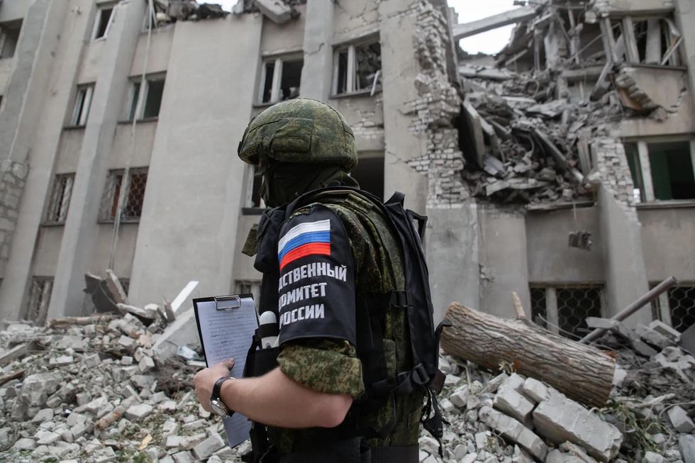 Soldier in front of damages from military strikes on Stakhanov, Lugansk People's Republic