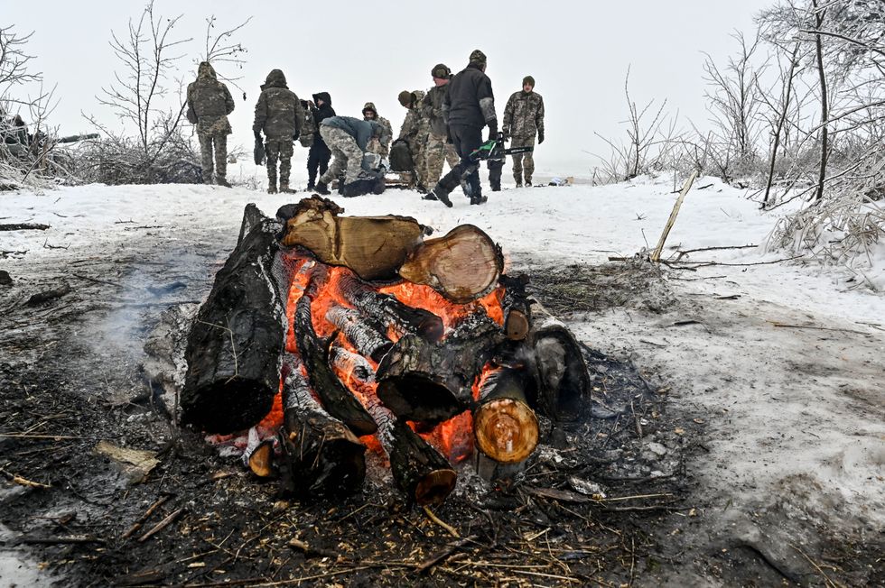 Soldiers of the 128th Separate Mountain Assault Brigade of the Zakarpattia Land Forces of the Armed Forces of Ukraine are seen near the fire during special training exercises