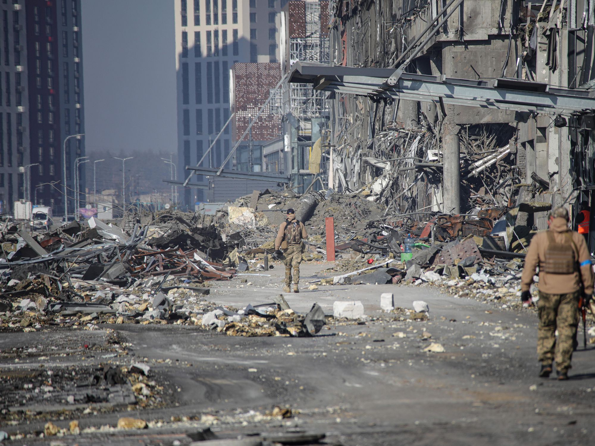 Soldiers walking by a shopping mall after it was hit by a missile strike carried out by Russian troops in the Podilskyi district of Kyiv