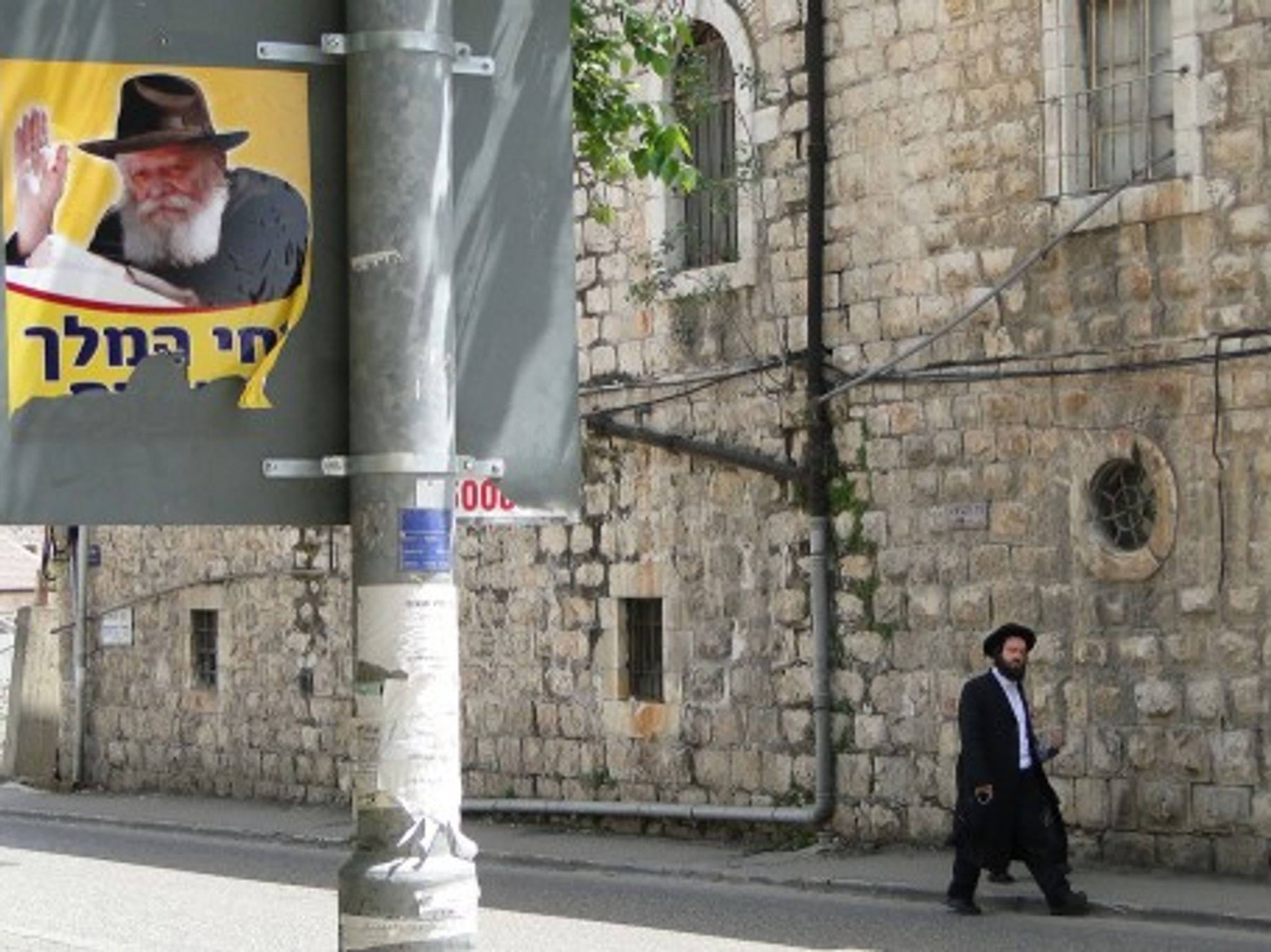 Street poster of Lubavitcher Rebbe, Rabbi Menachem Mendel Schneerson, with Orthodox pedestrian