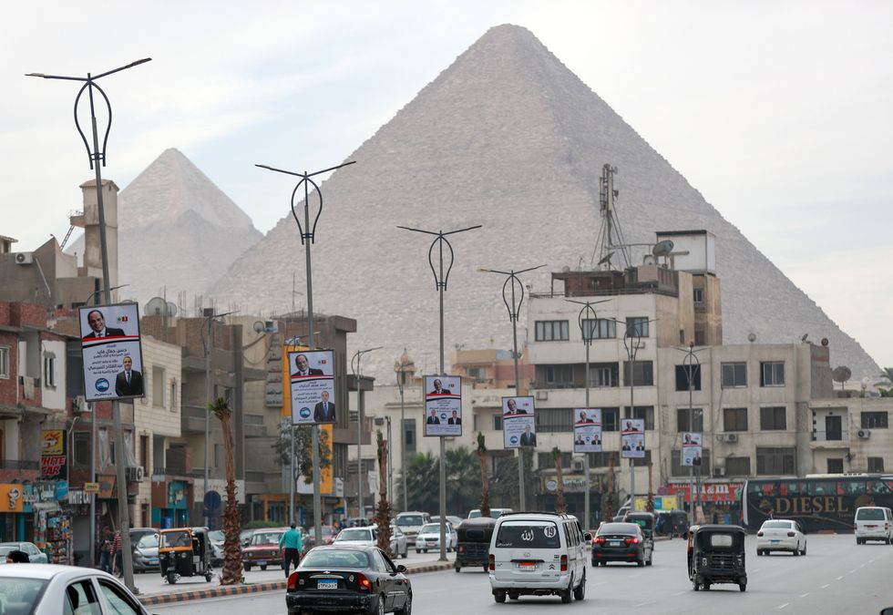 Street scene showing cars driving past electoral posters of Abdel-Fattah el-Sisi in Giza, Egypt, on Dec. 7, with the pyramids in the background