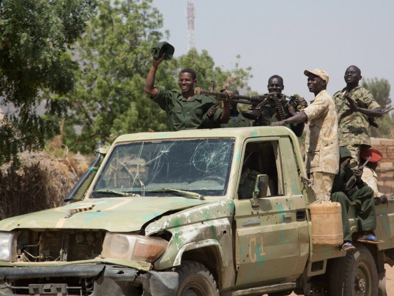 Sudanese soldiers riding on a truck after taking gunfire.