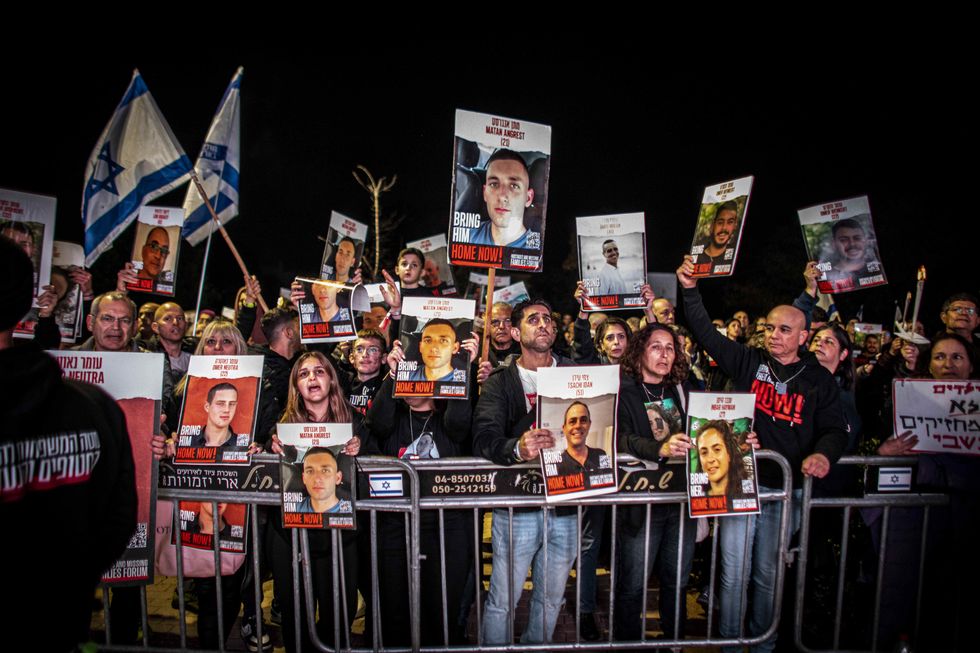 Supporters and families of Israeli hostages held in Gaza hold pictures of their loved ones during a protest outside the home of Prime Minister Benjamin Netanyahu.