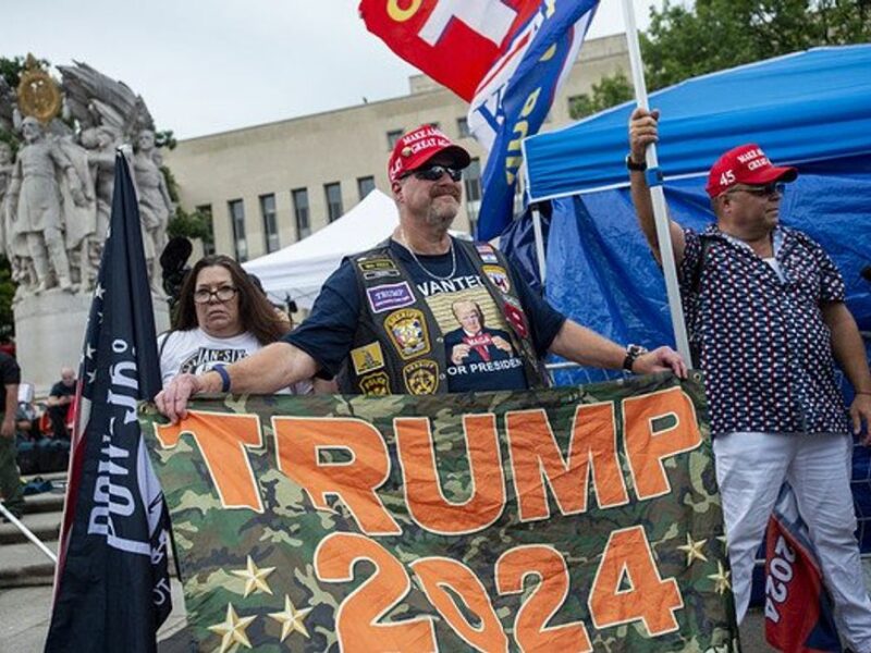Supporters of Donald J. Trump holding a "Trump 2024" banner.