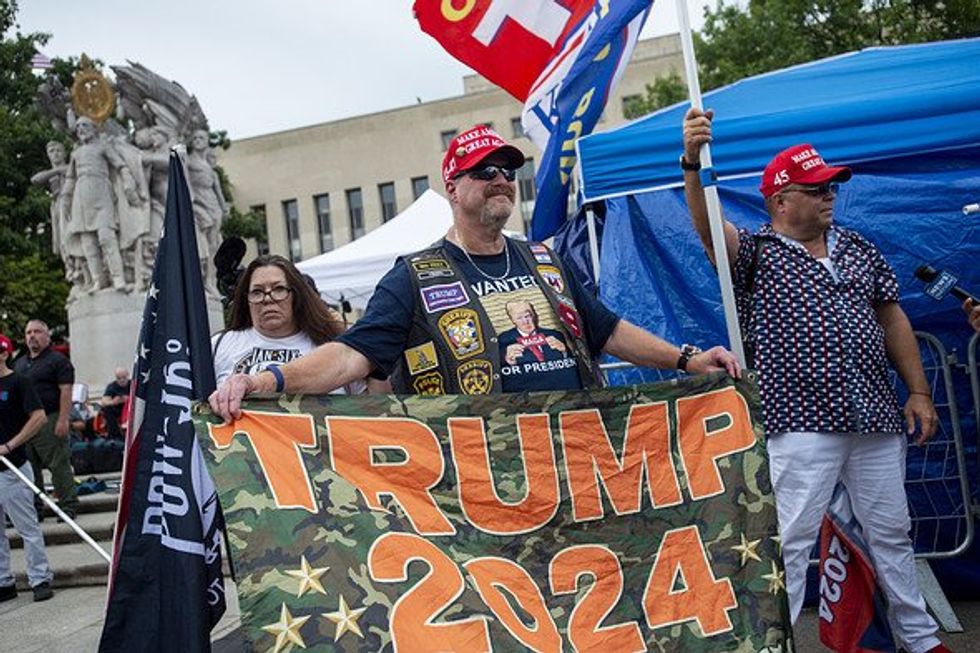 Supporters of Donald J. Trump holding a "Trump 2024" banner.
