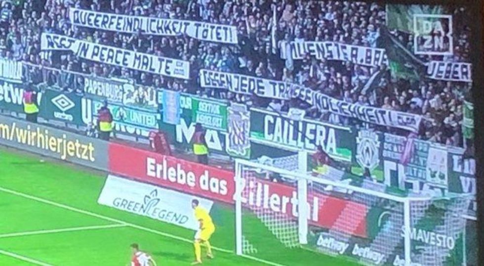 Supporters of the Bundesliga team SV Werder Bremen hold up rainbow flags and banners​