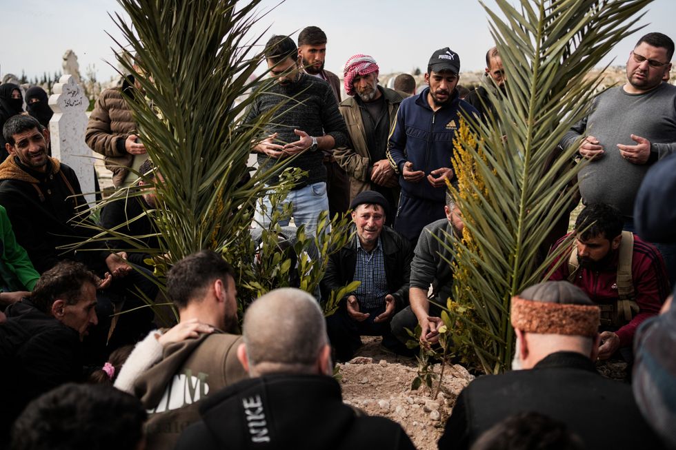 Syrian fighters and civilians attend the burial of a member of the Syrian security forces in Hama province, after he and 11 other colleagues were killed in an ambush by groups loyal to the ousted President Bashar al-Assad in Latakia.