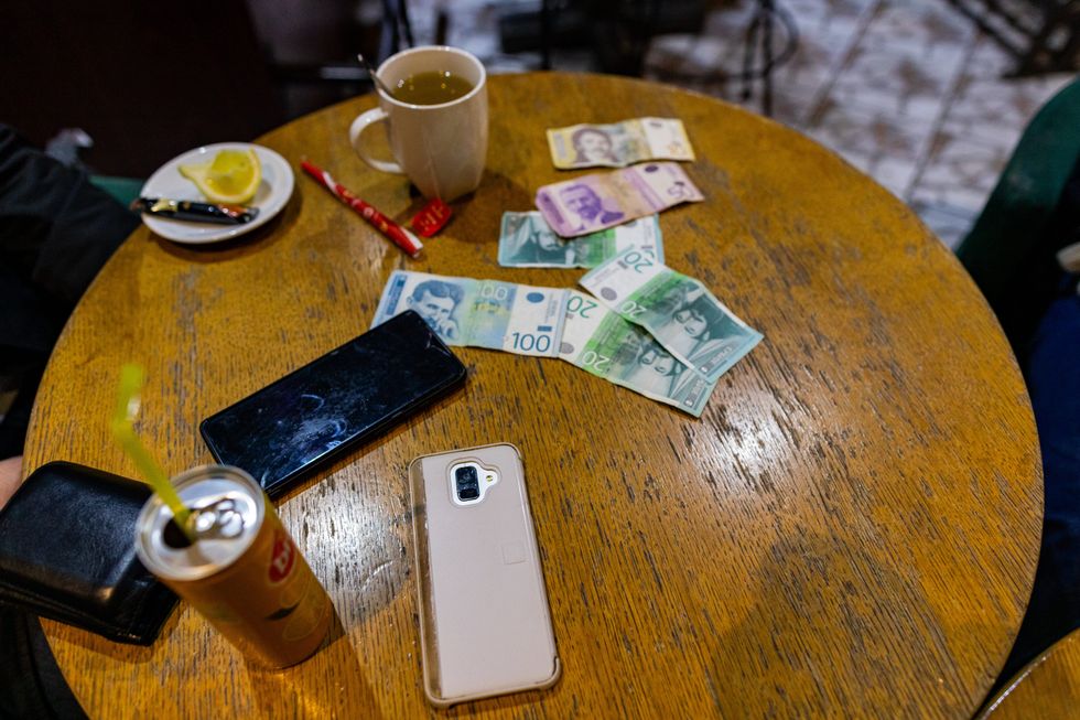 Table with change, phones, and drinks on it.
