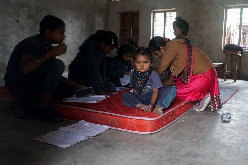 Teacher Rama Devi Dhakal, kneeling at right in bottom photo, leads children of varying ages through their lessons in a dimly lit classroom at Mechi Primary School, located near Gwalabasti.