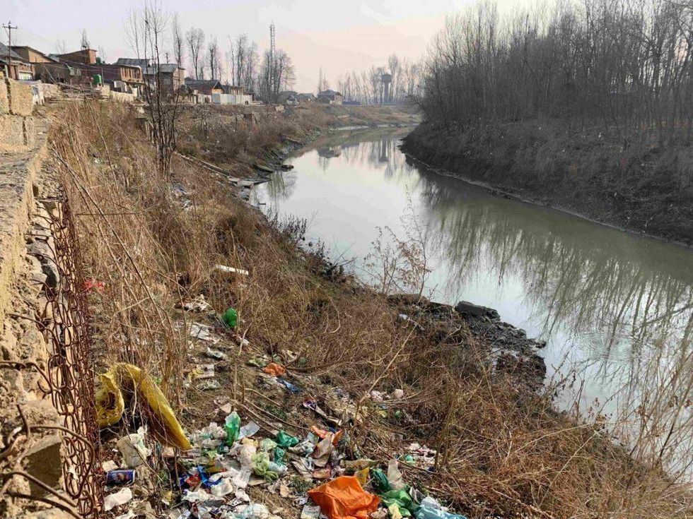 The banks of the Veshaw river, which provides drinking water to the village, strewn with trash.