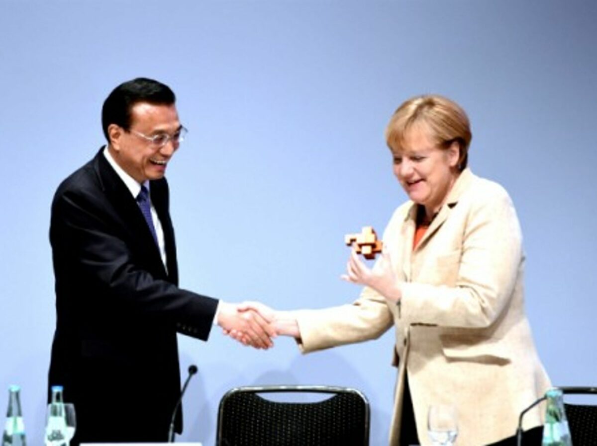 The Chinese Premier Li Keqiang presents a burr puzzle to German Chancellor Angela Merkel on October 10, 2014.
