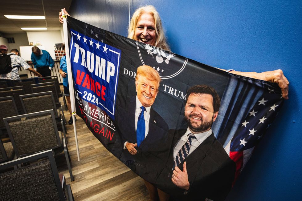 The Suncoast Liberty Fellowship, led by Rev. Robert Uhls (“Pastor Bob”), holds an election-eve ‘Prayer for America and President Trump’ event as a supporter waves a flag.