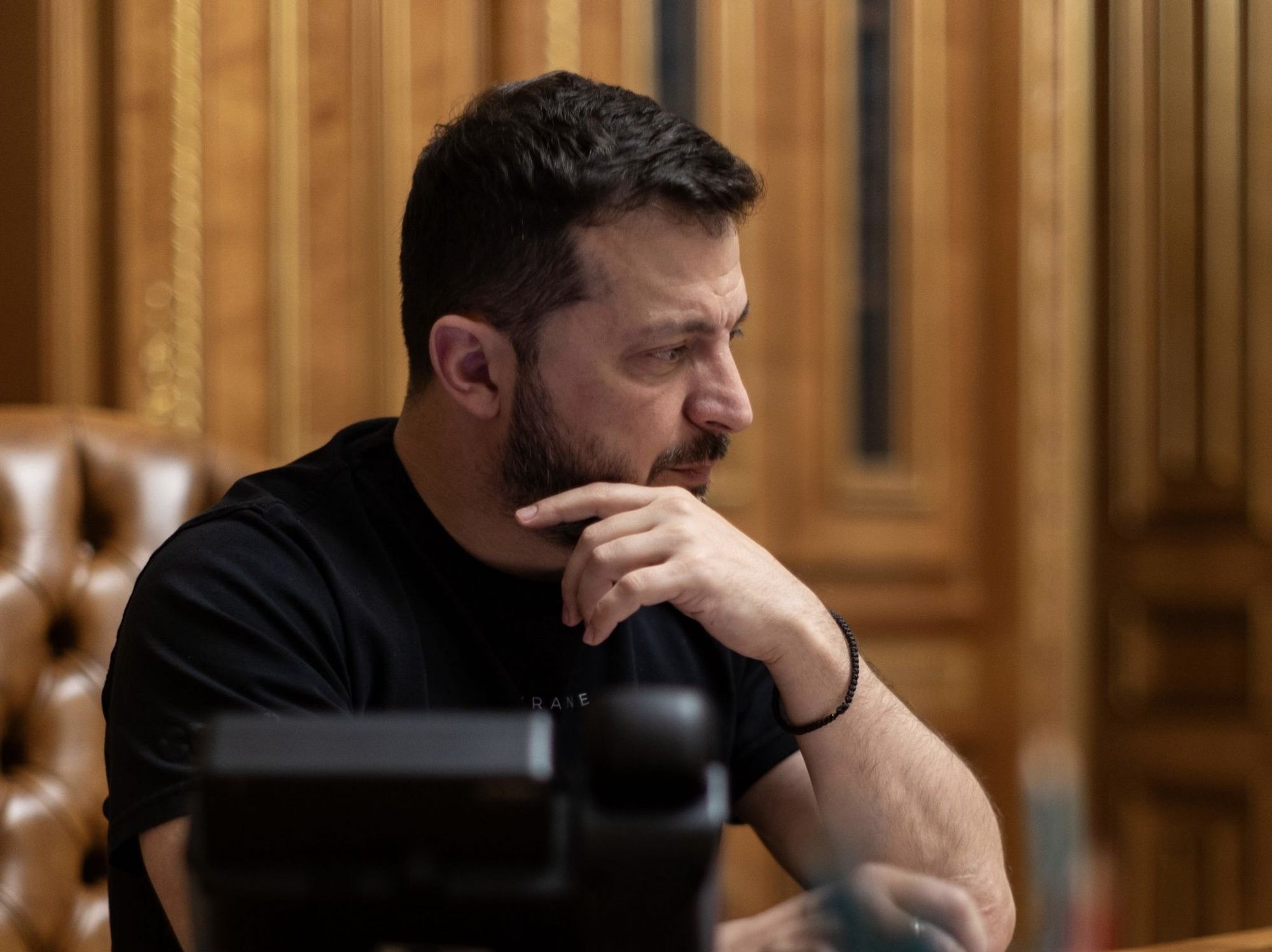 The Ukrainian President looks somber in his presidential office at his desk with a telephone in front of him.