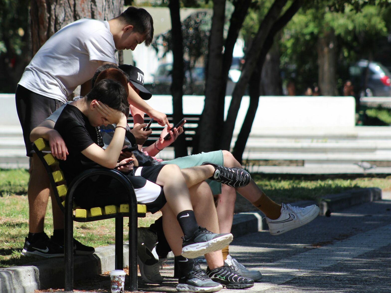 The youth spending time outside together, but focused on their digital screens.