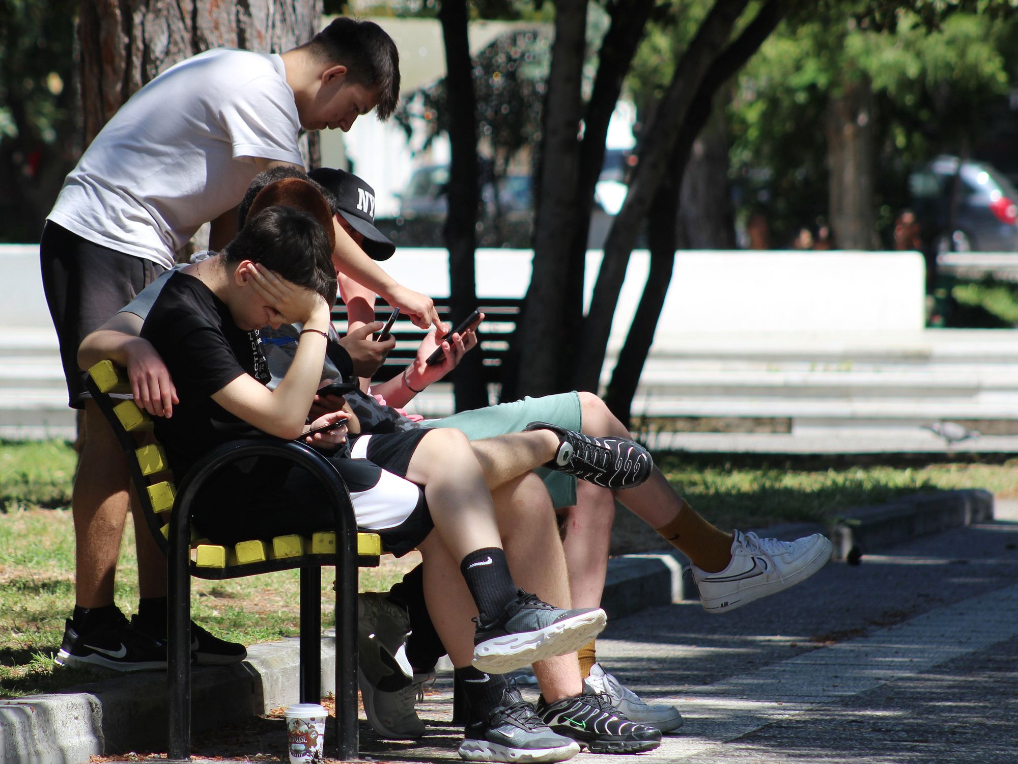 The youth spending time outside together, but focused on their digital screens.