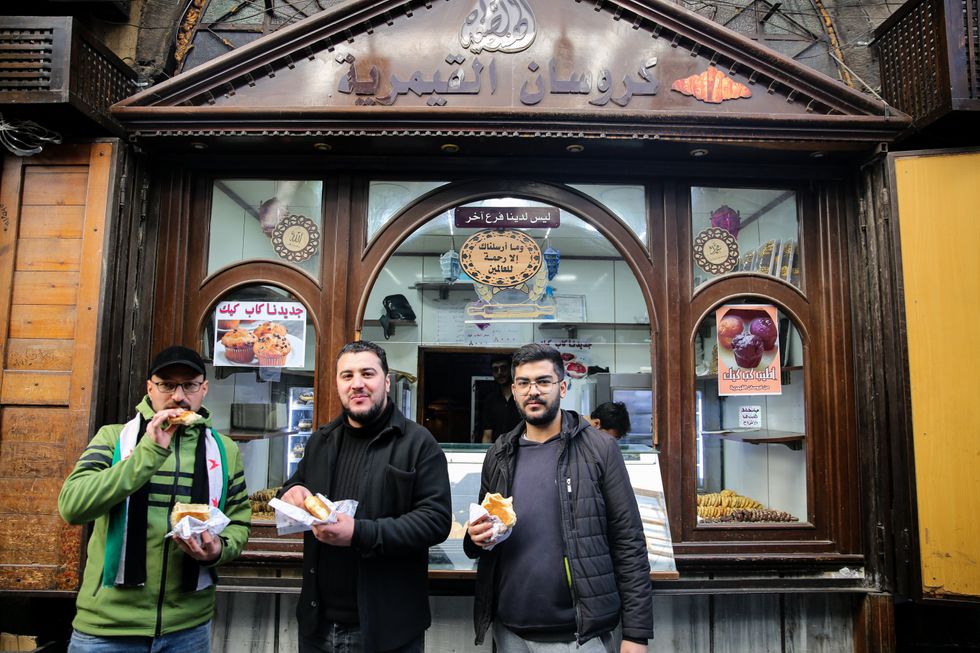 Three men eat their lunch outside an open shop for croissant and snacks in the city of Damascus in the aftermath of the fall of the government of Bashar Al-Assad in the Syrian capital, Damascus, Syria, Dec. 9, 2024.