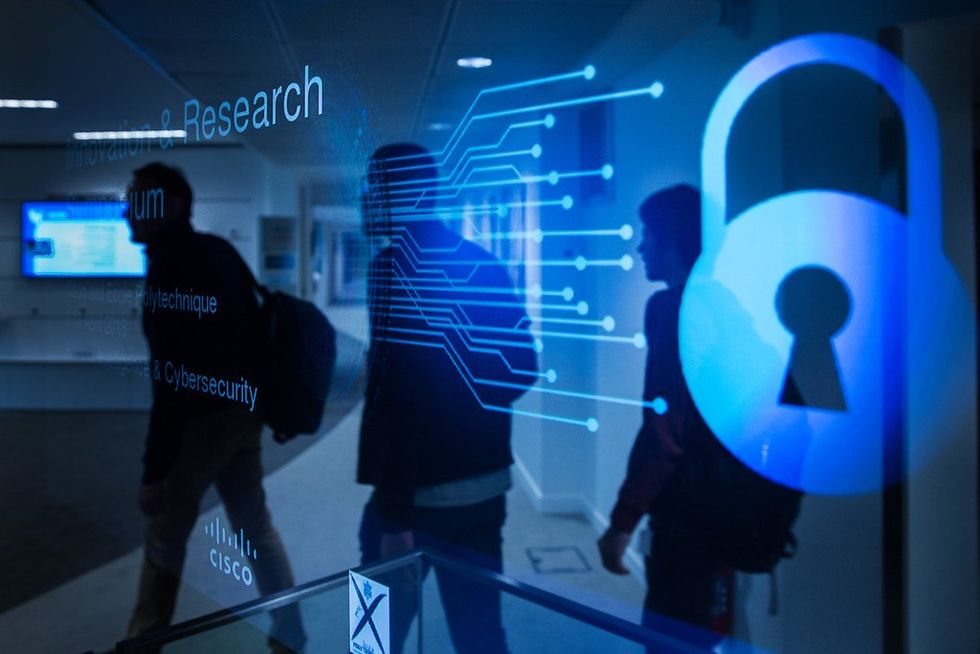 Three silhouettes with backpacks overlaid by a blue transparent cybersecurity screen.