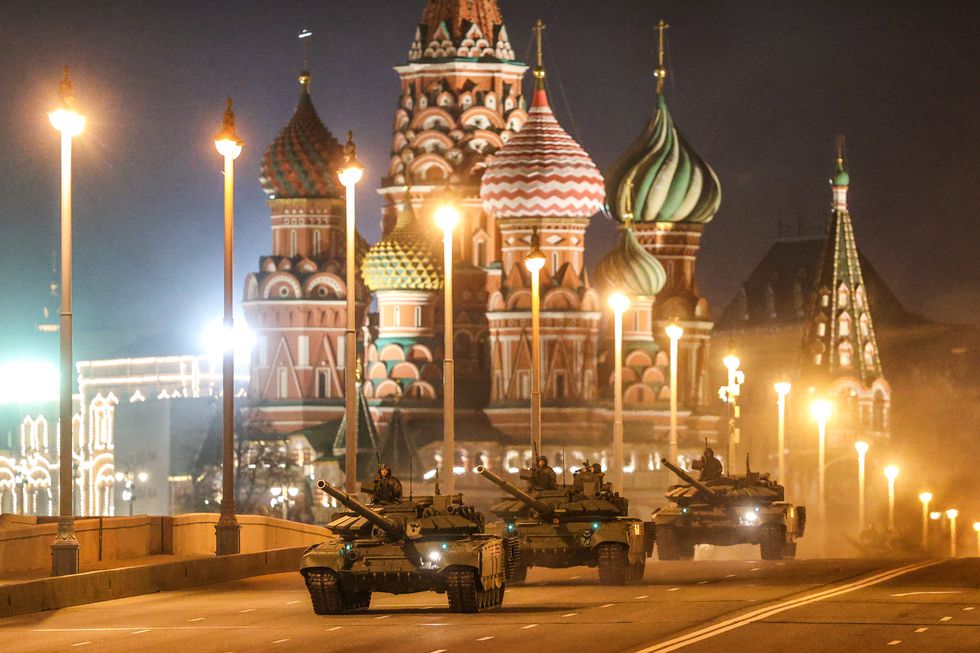 Three tanks drive along a street in front of Saint Basil's Cathedral in Moscow