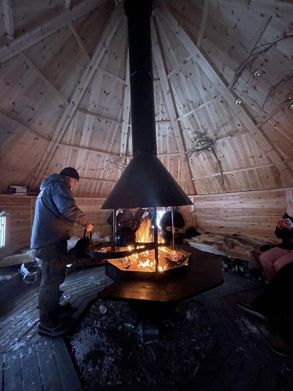 Travellers in a wooden house with an open fire.
