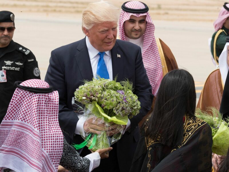 trump holding flowers surrounded by saudi officials