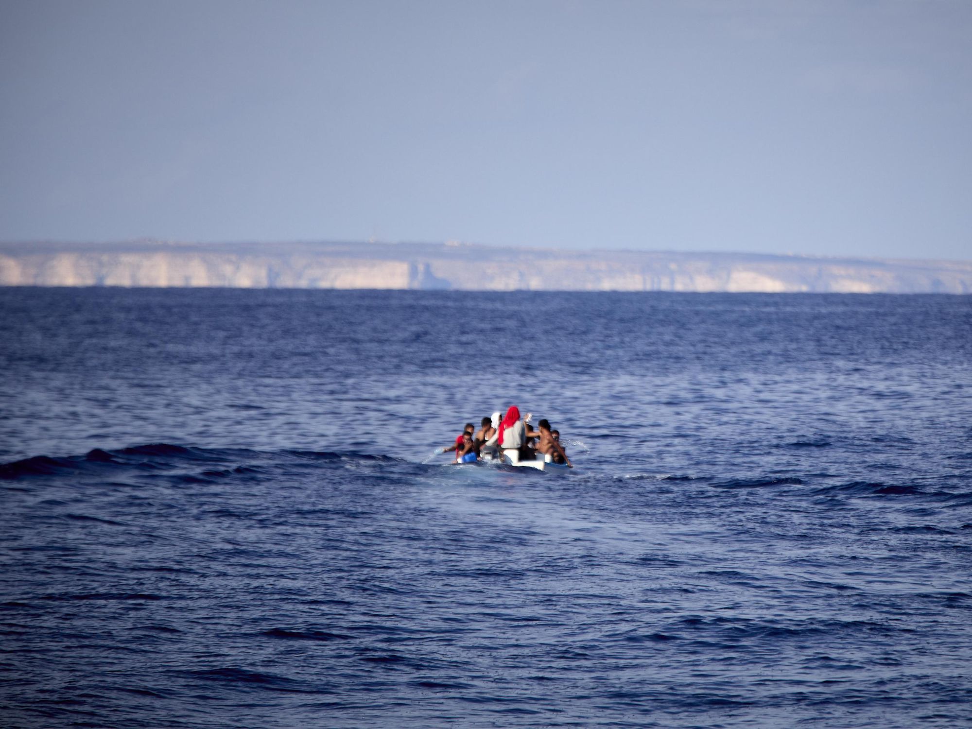 Tunisian migrants travel through the Mediterranean Sea in a small fishing boat towards the island of Lampedusa​