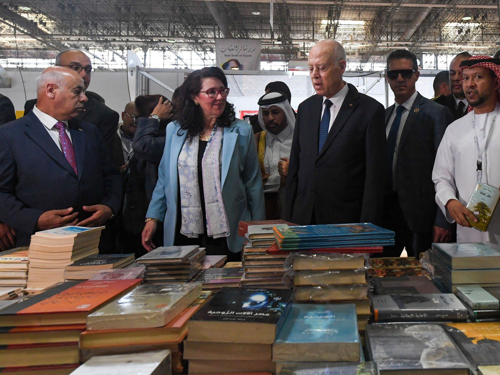 Tunisian President Kais Said and his entourage stand infront of a table piled with books