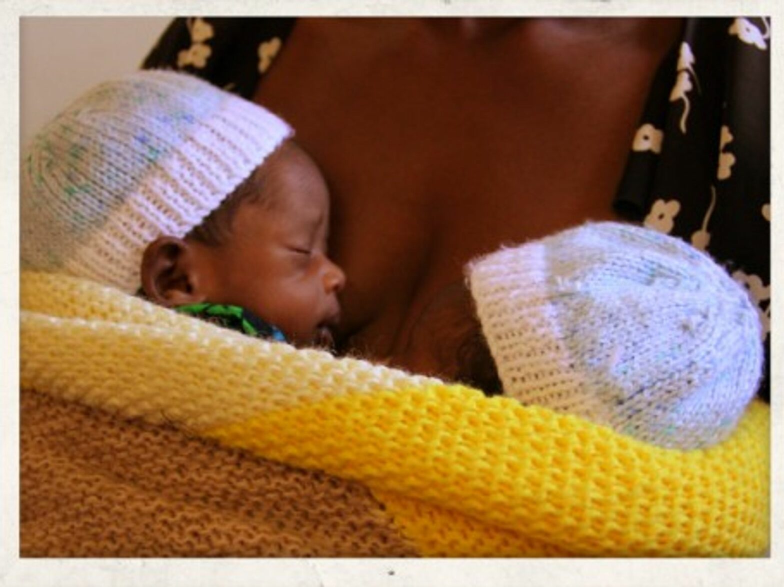 Twin boys strapped to their grandmotherâ€™s chest in Malawi.
