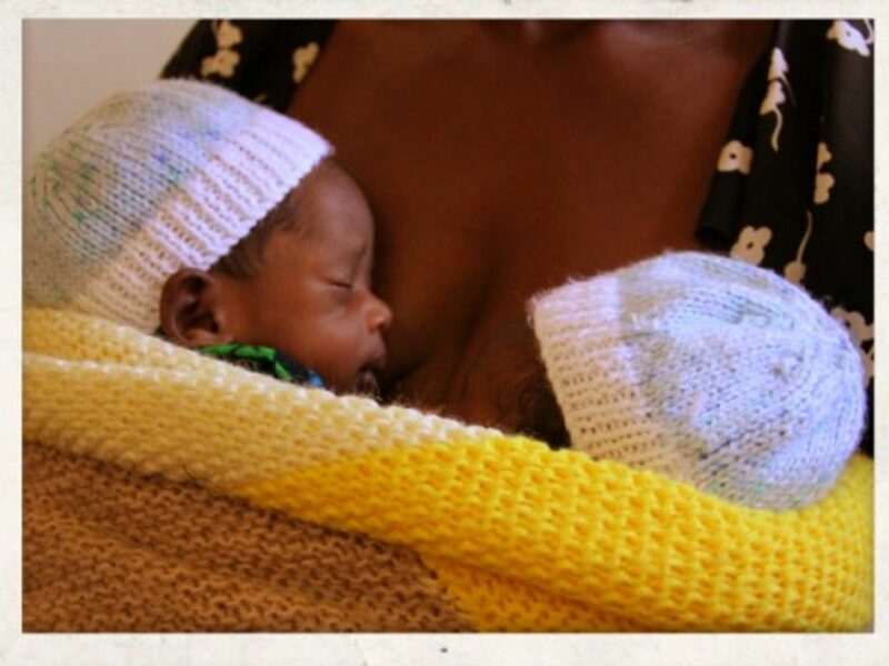 Twin boys strapped to their grandmotherâ€™s chest in Malawi.