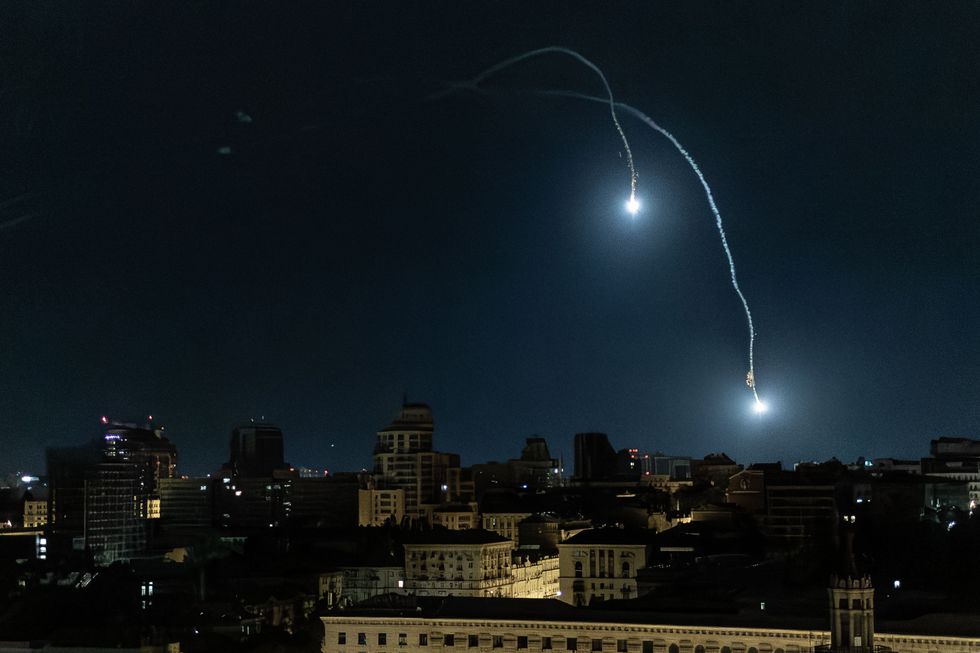 Two bright, firework-like missiles light up the night sky over Kyiv